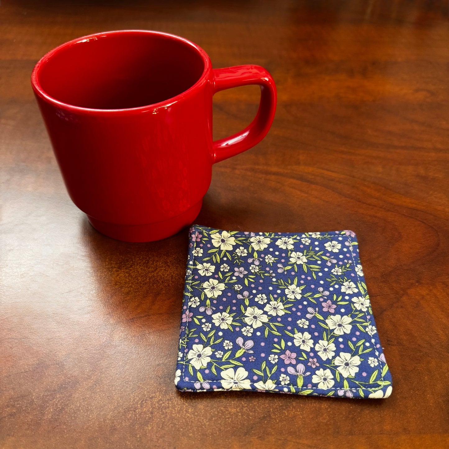 Elevate your space with this playful 100% cotton blue floral coaster. Featuring a vibrant and stylish blue floral print, this coaster brings a touch of floral and fun to your home. Crafted with an absorbent cotton batting layer inside, it's designed to soak up condensation and protect your furniture from unsightly water rings and spills. Perfect for coffee mugs, glasses, or teacups, this durable and machine-washable coaster is a delightful addition to your kitchen or living room. Elevate your home decor wit