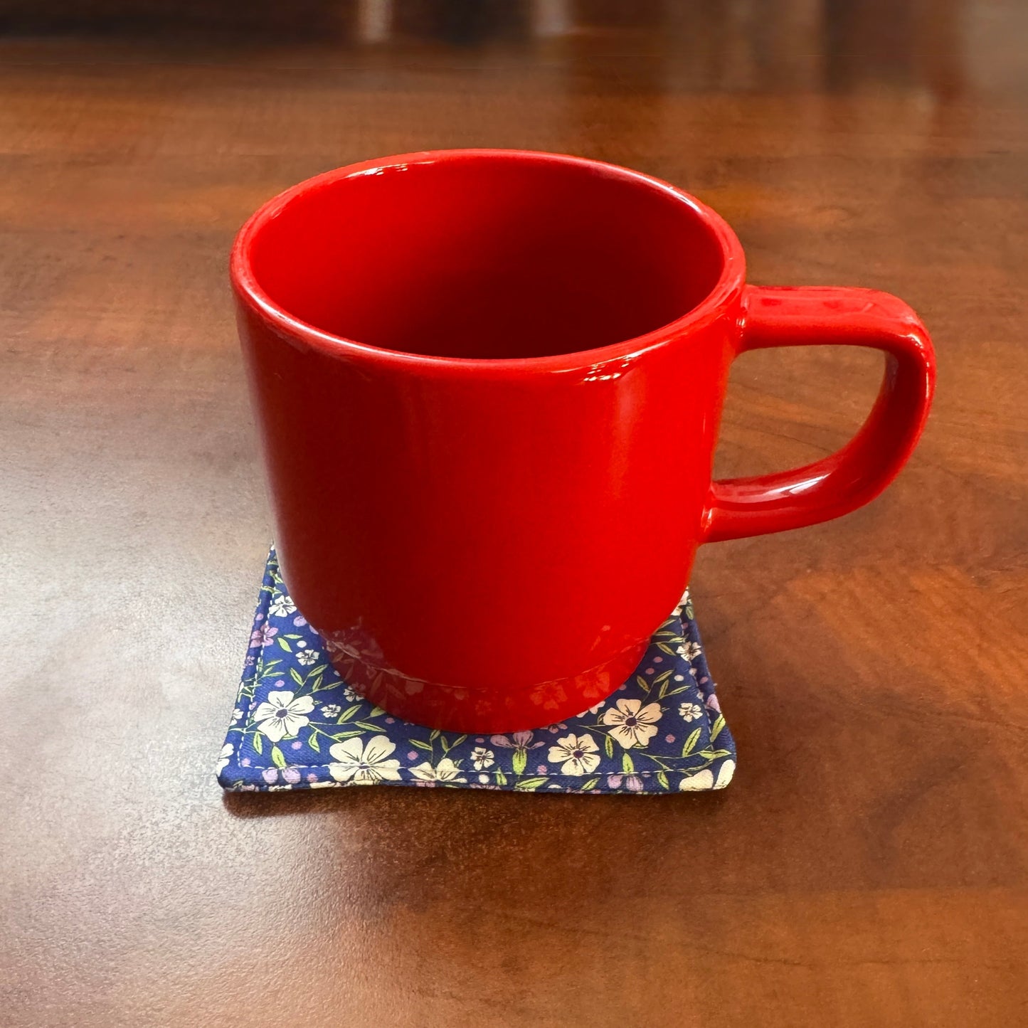Elevate your space with this playful 100% cotton blue floral coaster. Featuring a vibrant and stylish blue floral print, this coaster brings a touch of floral and fun to your home. Crafted with an absorbent cotton batting layer inside, it's designed to soak up condensation and protect your furniture from unsightly water rings and spills. Perfect for coffee mugs, glasses, or teacups, this durable and machine-washable coaster is a delightful addition to your kitchen or living room. Elevate your home decor wit