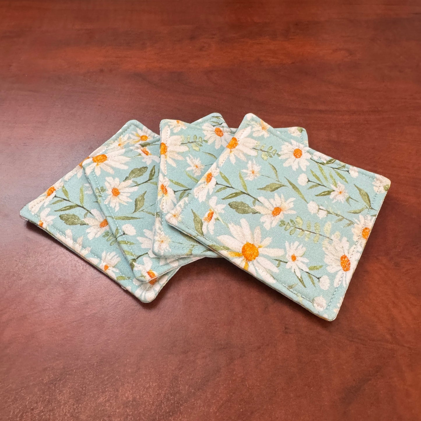 Elevate your space with this playful 100% cotton daisy coaster. Featuring a vibrant and stylish daisy print, this coaster brings a touch of tropical flair and fun to your home. Crafted with an absorbent cotton batting layer inside, it's designed to soak up condensation and protect your furniture from unsightly water rings and spills. Perfect for coffee mugs, glasses, or teacups, this durable and machine-washable coaster is a delightful addition to your kitchen or living room. Elevate your home decor with th