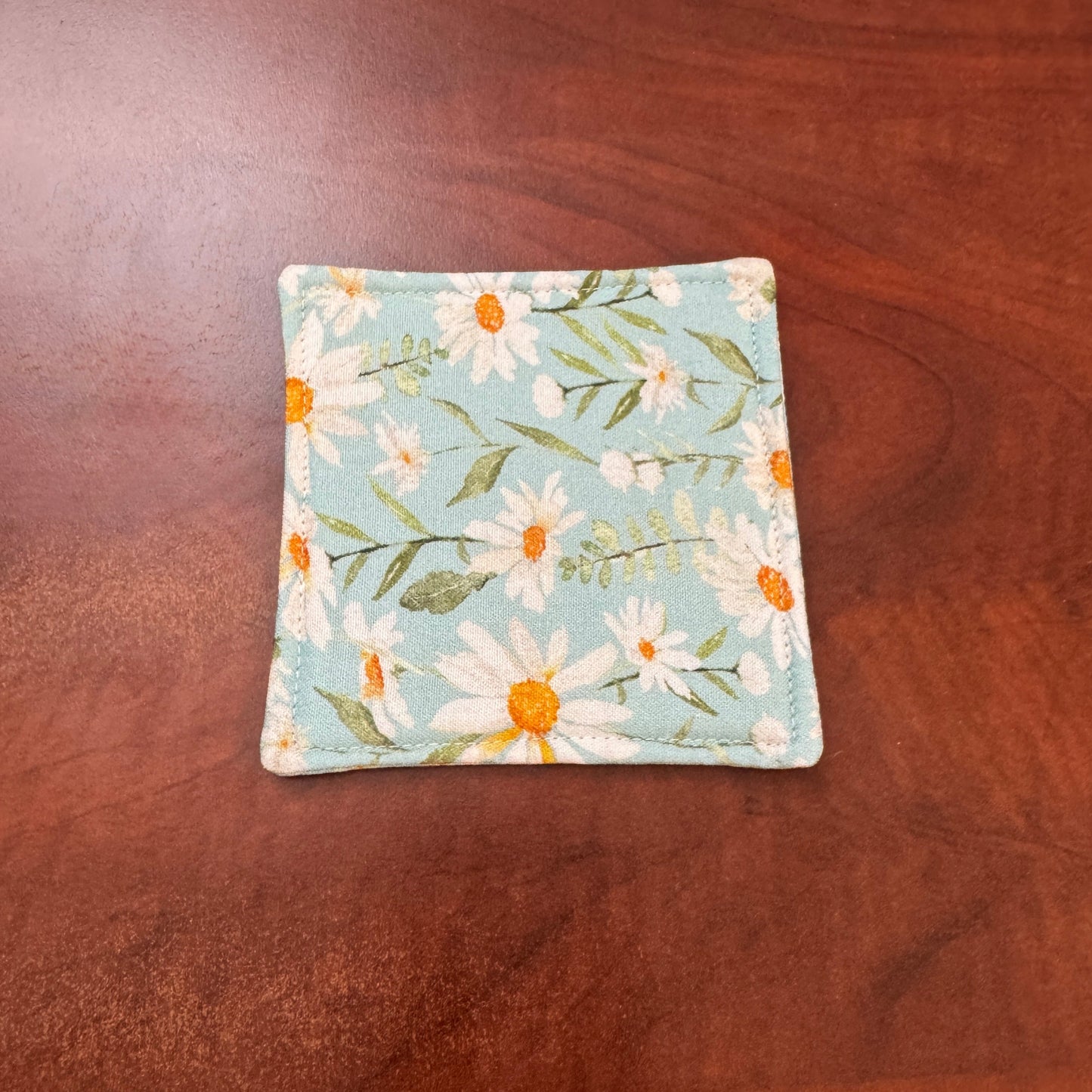 Elevate your space with this playful 100% cotton daisy coaster. Featuring a vibrant and stylish daisy print, this coaster brings a touch of tropical flair and fun to your home. Crafted with an absorbent cotton batting layer inside, it's designed to soak up condensation and protect your furniture from unsightly water rings and spills. Perfect for coffee mugs, glasses, or teacups, this durable and machine-washable coaster is a delightful addition to your kitchen or living room. Elevate your home decor with th