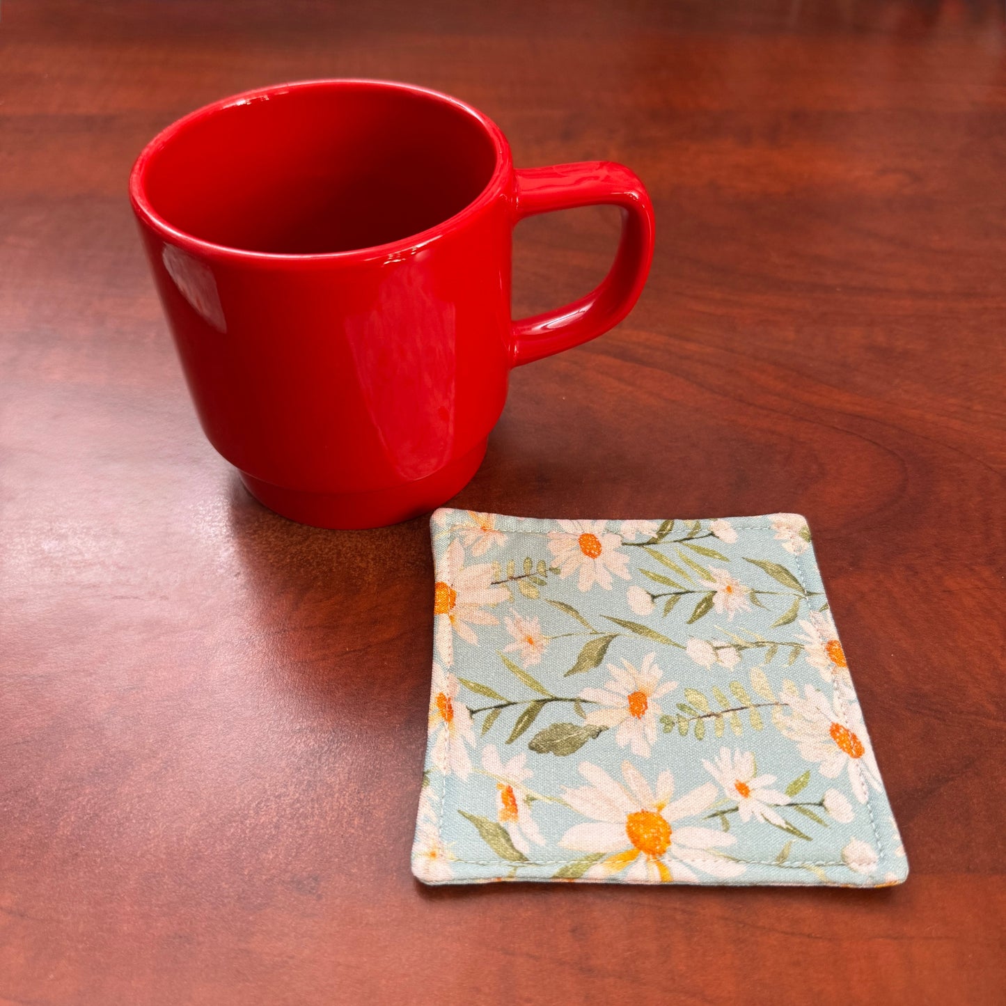 Elevate your space with this playful 100% cotton daisy coaster. Featuring a vibrant and stylish daisy print, this coaster brings a touch of tropical flair and fun to your home. Crafted with an absorbent cotton batting layer inside, it's designed to soak up condensation and protect your furniture from unsightly water rings and spills. Perfect for coffee mugs, glasses, or teacups, this durable and machine-washable coaster is a delightful addition to your kitchen or living room. Elevate your home decor with th