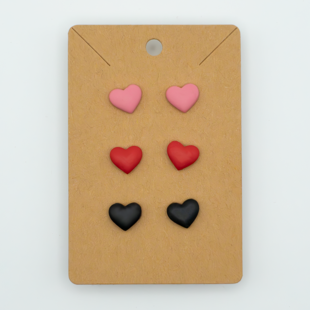 Elevate your everyday look with this stylish pack of three heart stud earrings. Featuring the colors pink, red, and black, these versatile earrings are perfect for any occasion.