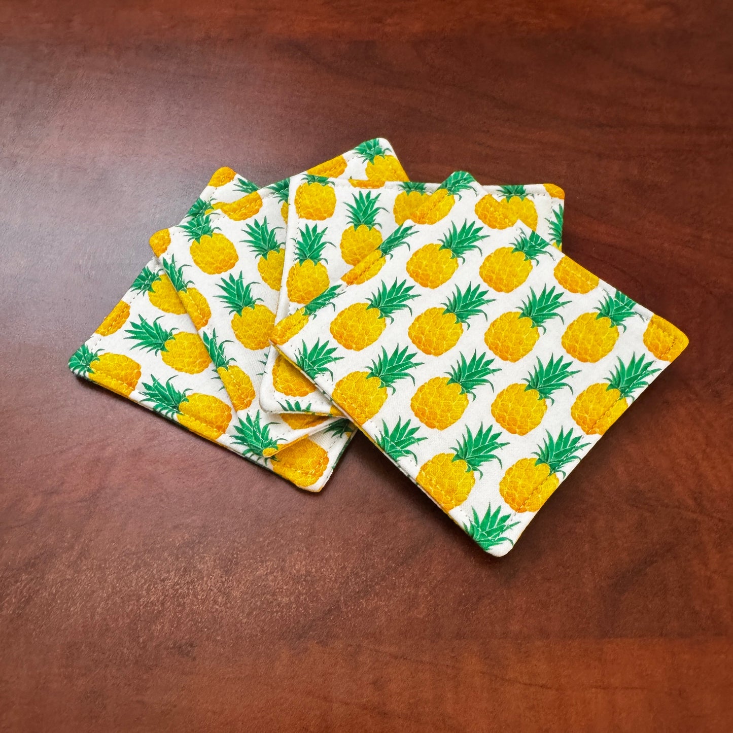 Keep your surfaces safe and stylish with our 100% cotton pineapple coaster. This charming coaster features a vibrant pineapple print that adds a touch of fresh, fruity fun to any room. Crafted with an absorbent cotton batting layer inside, it's designed to soak up condensation and protect your furniture from unsightly water rings and spills. Perfect for coffee mugs, glasses, or teacups, this durable and machine-washable coaster is a delightful addition to your kitchen or living room. Elevate your home decor