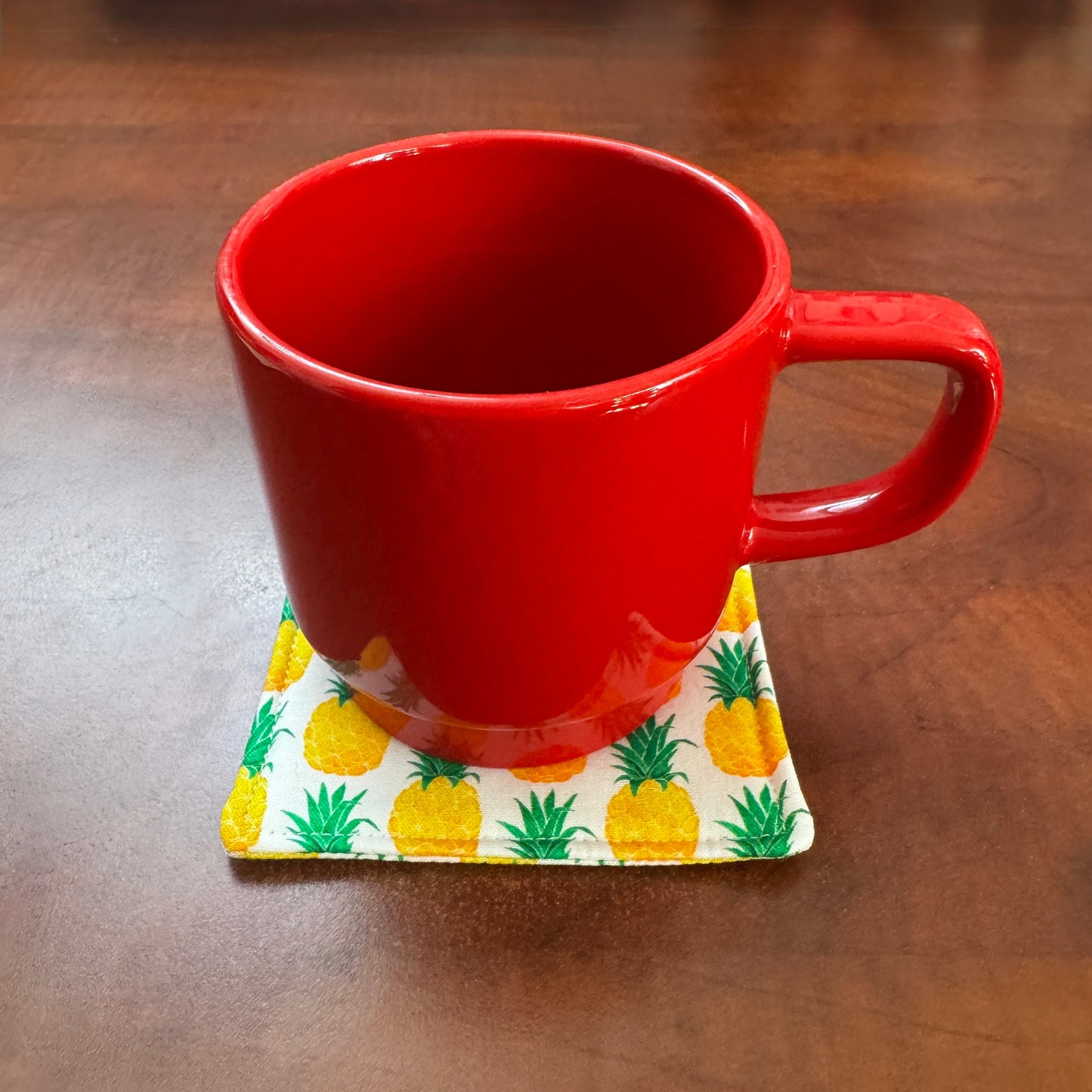 Keep your surfaces safe and stylish with our 100% cotton pineapple coaster. This charming coaster features a vibrant pineapple print that adds a touch of fresh, fruity fun to any room. Crafted with an absorbent cotton batting layer inside, it's designed to soak up condensation and protect your furniture from unsightly water rings and spills. Perfect for coffee mugs, glasses, or teacups, this durable and machine-washable coaster is a delightful addition to your kitchen or living room. Elevate your home decor