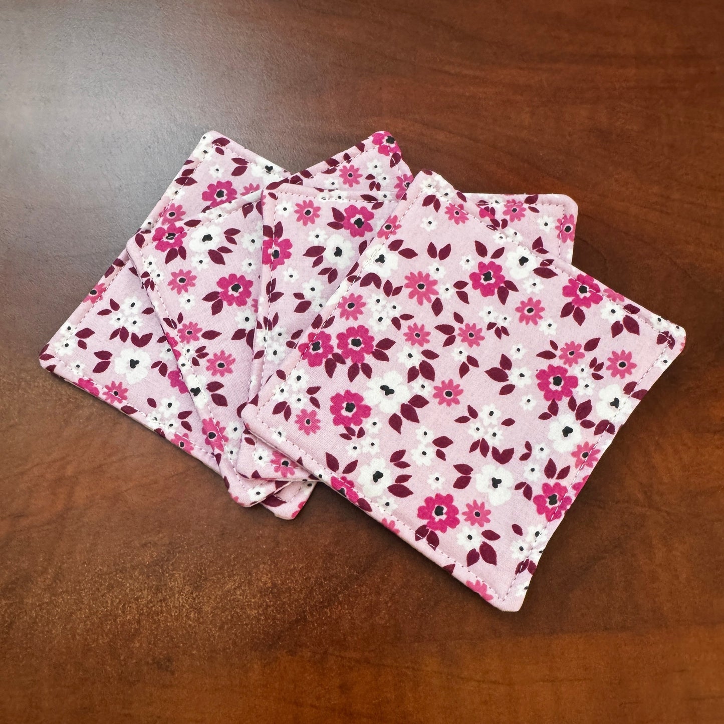 Elevate your space with this playful 100% cotton pink floral coaster. Featuring a vibrant and stylish floral print, this coaster brings a touch of floral and fun to your home. Crafted with an absorbent cotton batting layer inside, it's designed to soak up condensation and protect your furniture from unsightly water rings and spills. Perfect for coffee mugs, glasses, or teacups, this durable and machine-washable coaster is a delightful addition to your kitchen or living room. Elevate your home decor with thi