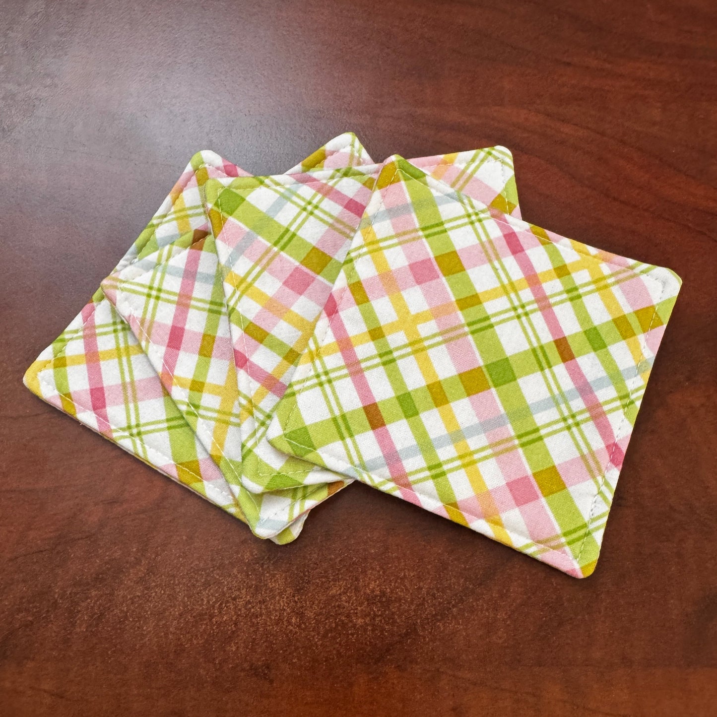 Elevate your space with this playful 100% cotton pink and green plaid coaster. Featuring a vibrant and stylish pink and green plaid print, this coaster brings a touch of retro fun to your home. Crafted with an absorbent cotton batting layer inside, it's designed to soak up condensation and protect your furniture from unsightly water rings and spills. Perfect for coffee mugs, glasses, or teacups, this durable and machine-washable coaster is a delightful addition to your kitchen or living room. Elevate your h