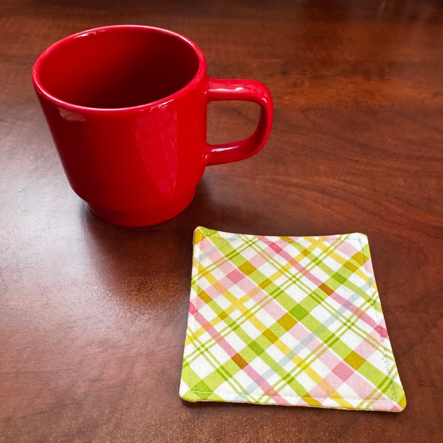 Elevate your space with this playful 100% cotton pink and green plaid coaster. Featuring a vibrant and stylish pink and green plaid print, this coaster brings a touch of retro fun to your home. Crafted with an absorbent cotton batting layer inside, it's designed to soak up condensation and protect your furniture from unsightly water rings and spills. Perfect for coffee mugs, glasses, or teacups, this durable and machine-washable coaster is a delightful addition to your kitchen or living room. Elevate your h