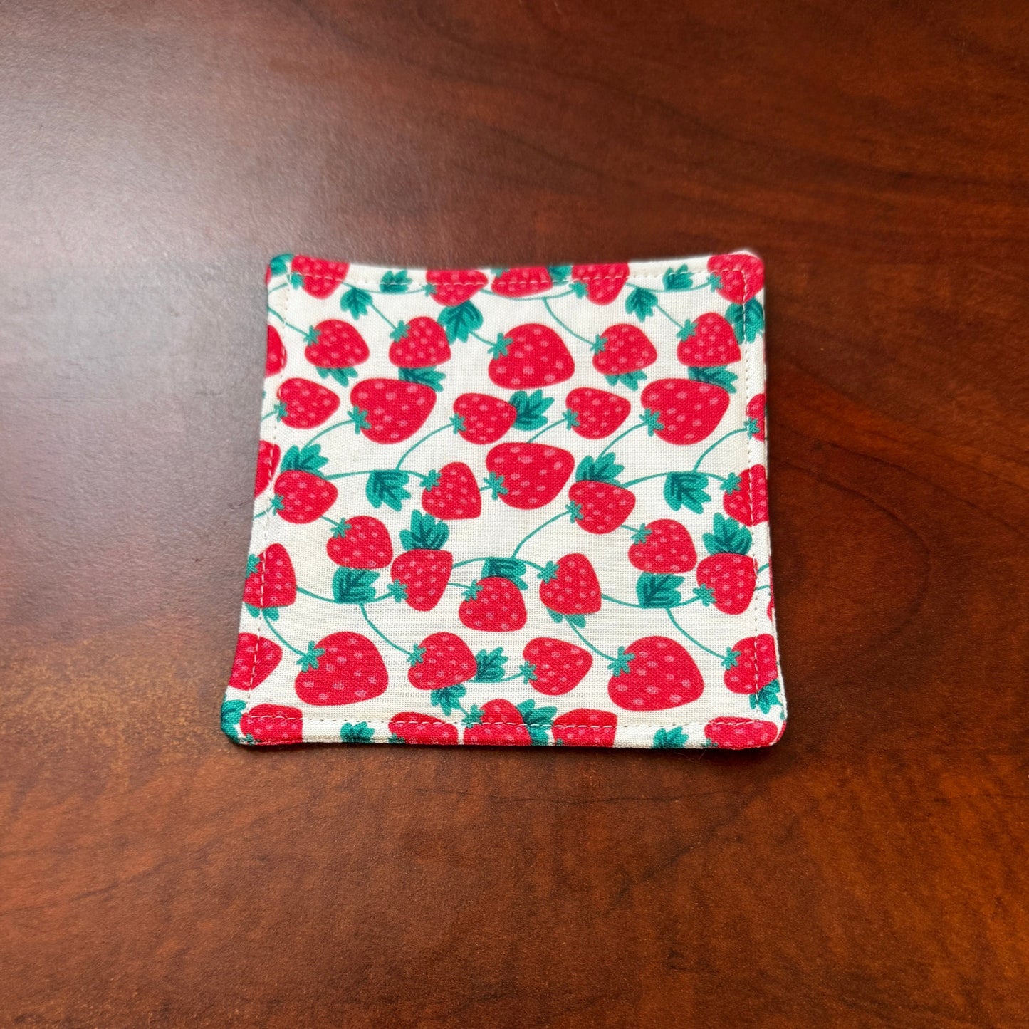 Keep your surfaces safe and stylish with our 100% cotton strawberry coaster. This charming coaster features a vibrant strawberry print that adds a touch of fresh, fruity fun to any room. Crafted with an absorbent cotton batting layer inside, it's designed to soak up condensation and protect your furniture from unsightly water rings and spills. Perfect for coffee mugs, glasses, or teacups, this durable and machine-washable coaster is a delightful addition to your kitchen or living room. Elevate your home dec