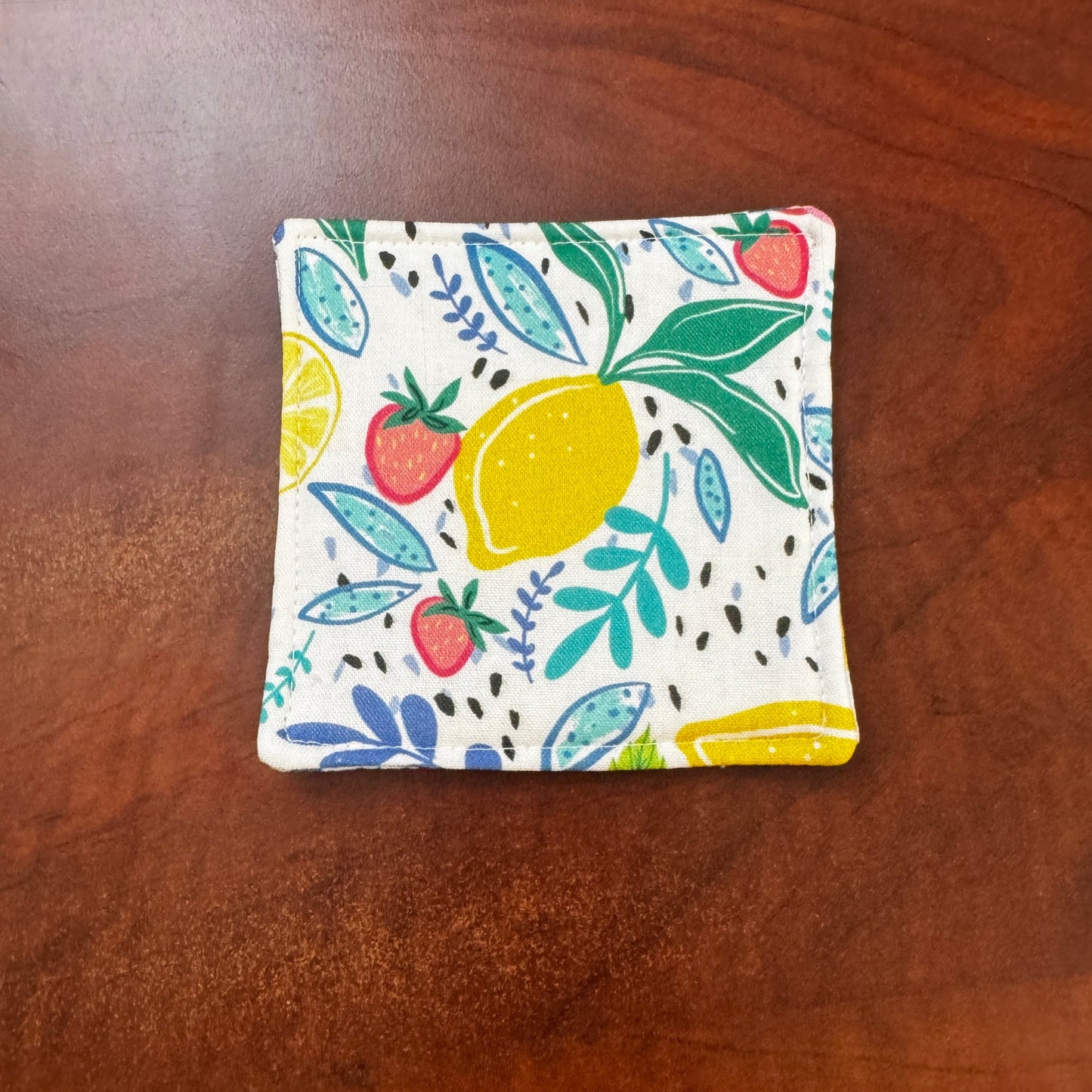 Keep your surfaces safe and stylish with our 100% cotton strawberry and lemon coaster. This charming coaster features a vibrant strawberry and lemon print that adds a touch of fresh, fruity fun to any room. Crafted with an absorbent cotton batting layer inside, it's designed to soak up condensation and protect your furniture from unsightly water rings and spills. Perfect for coffee mugs, glasses, or teacups, this durable and machine-washable coaster is a delightful addition to your kitchen or living room. E
