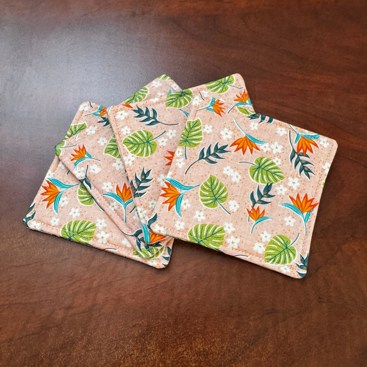 Elevate your space with this playful 100% cotton tropical coaster. Featuring a vibrant and stylish tropical print, this coaster brings a touch of tropical flair and fun to your home. Crafted with an absorbent cotton batting layer inside, it's designed to soak up condensation and protect your furniture from unsightly water rings and spills. Perfect for coffee mugs, glasses, or teacups, this durable and machine-washable coaster is a delightful addition to your kitchen or living room. Elevate your home decor w