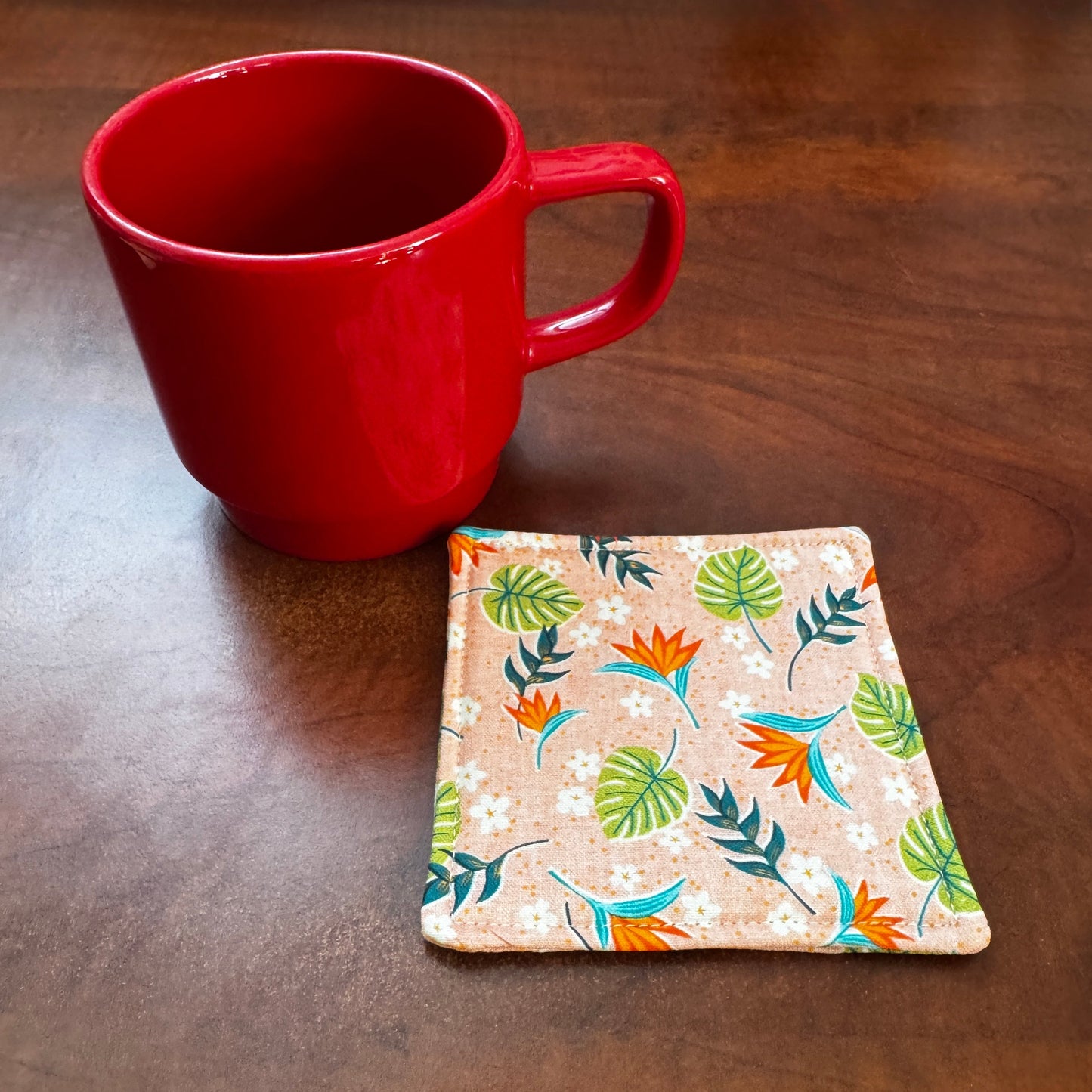 Elevate your space with this playful 100% cotton tropical coaster. Featuring a vibrant and stylish tropical print, this coaster brings a touch of tropical flair and fun to your home. Crafted with an absorbent cotton batting layer inside, it's designed to soak up condensation and protect your furniture from unsightly water rings and spills. Perfect for coffee mugs, glasses, or teacups, this durable and machine-washable coaster is a delightful addition to your kitchen or living room. Elevate your home decor w