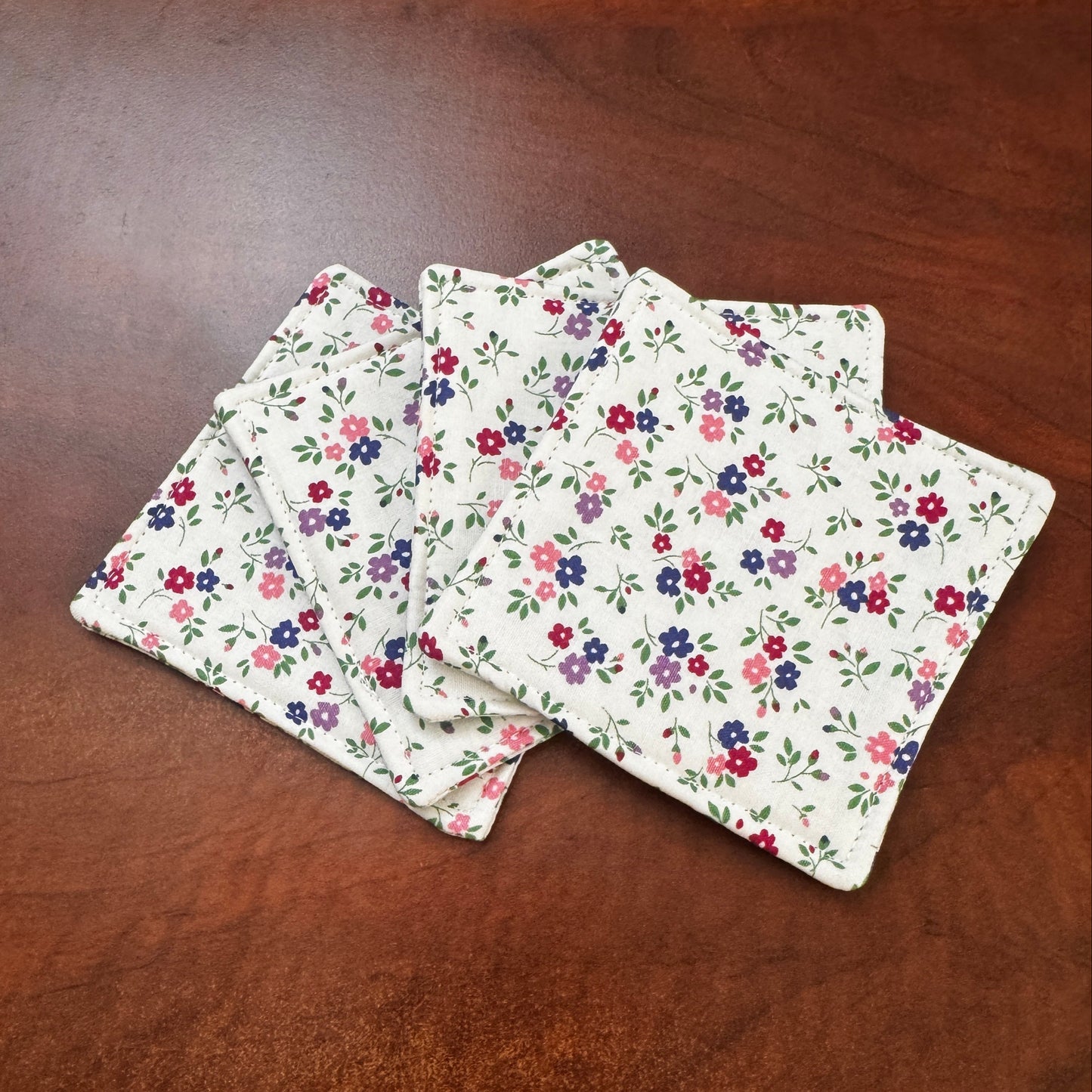 Elevate your space with this playful 100% cotton white floral coaster. Featuring a vibrant and stylish floral print, this coaster brings a touch of floral and fun to your home. Crafted with an absorbent cotton batting layer inside, it's designed to soak up condensation and protect your furniture from unsightly water rings and spills. Perfect for coffee mugs, glasses, or teacups, this durable and machine-washable coaster is a delightful addition to your kitchen or living room. Elevate your home decor with th