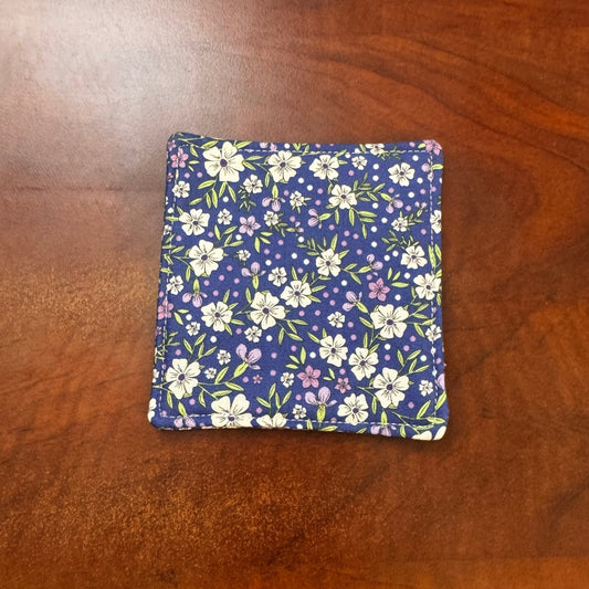 Elevate your space with this playful 100% cotton blue floral coaster. Featuring a vibrant and stylish blue floral print, this coaster brings a touch of floral and fun to your home. Crafted with an absorbent cotton batting layer inside, it's designed to soak up condensation and protect your furniture from unsightly water rings and spills. Perfect for coffee mugs, glasses, or teacups, this durable and machine-washable coaster is a delightful addition to your kitchen or living room. Elevate your home decor wit