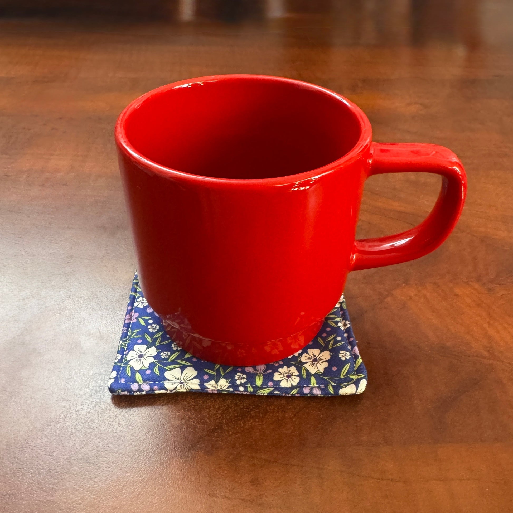 Elevate your space with this playful 100% cotton blue floral coaster. Featuring a vibrant and stylish blue floral print, this coaster brings a touch of floral and fun to your home. Crafted with an absorbent cotton batting layer inside, it's designed to soak up condensation and protect your furniture from unsightly water rings and spills. Perfect for coffee mugs, glasses, or teacups, this durable and machine-washable coaster is a delightful addition to your kitchen or living room. Elevate your home decor wit