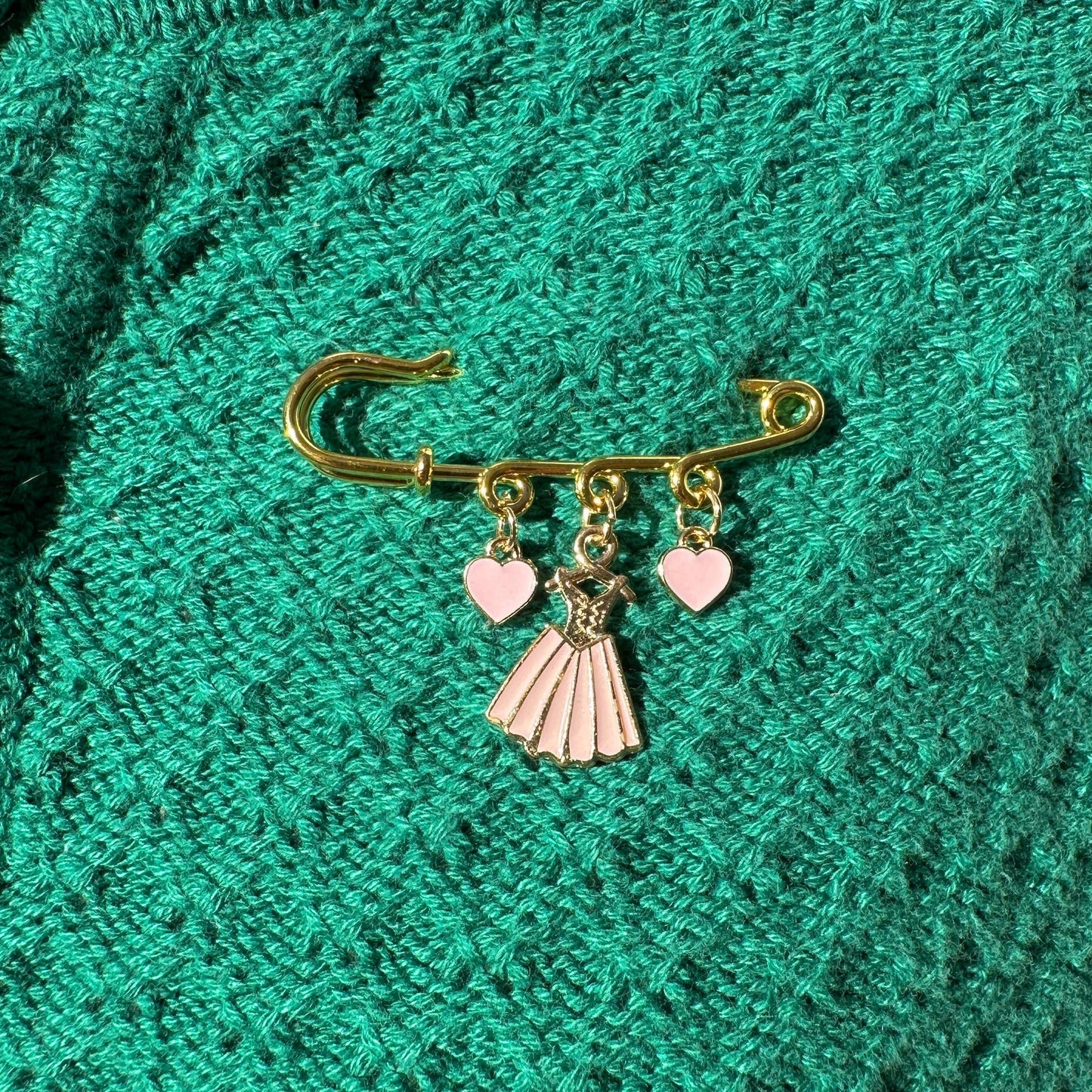 Elevate your Valentines Day or Galentines Day with this adorable gold iron pin brooch featuring pink dress enamel charms. Perfect for adding a touch of love to any outfit.