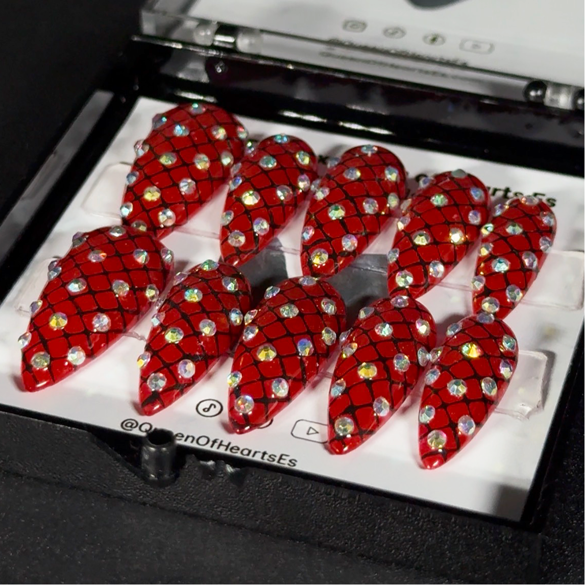 Get ready for "The Net of Desires" and embrace vintage glamour with these stunning press-on nails, featuring a rich red base and a delicate, sparkling hairnet pattern. Adorned with brilliant rhinestones, this set pays homage to the iconic, original sparkly hairnets from Wearable Art by Jenny Dame. Each set is a miniature work of art—meticulously hand-painted and designed to bring a unique, dramatic flair to any occasion. No time for salon appointments? Say hello to instant glamour that’s ready whenever.