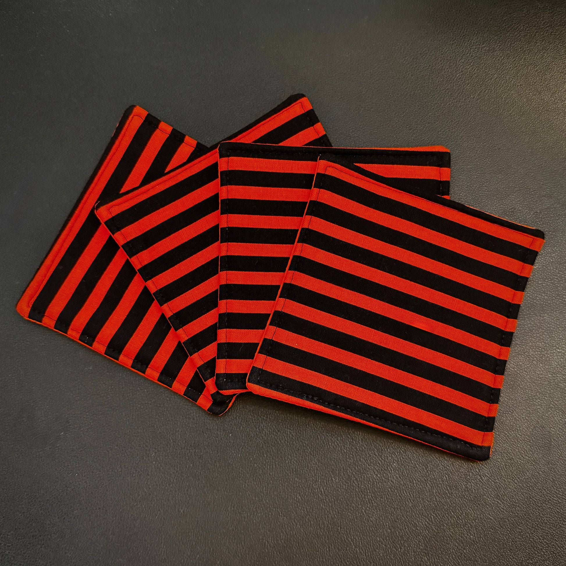 Embrace a classic, timeless pattern with a dark alternative twist with this matching set of 4 handmade cotton coasters. Featuring a striking, high-contrast linear design, these drink mats perfectly channel vintage punk rock, timeless goth culture, and a subtle nod to spooky cinematic aesthetics.
