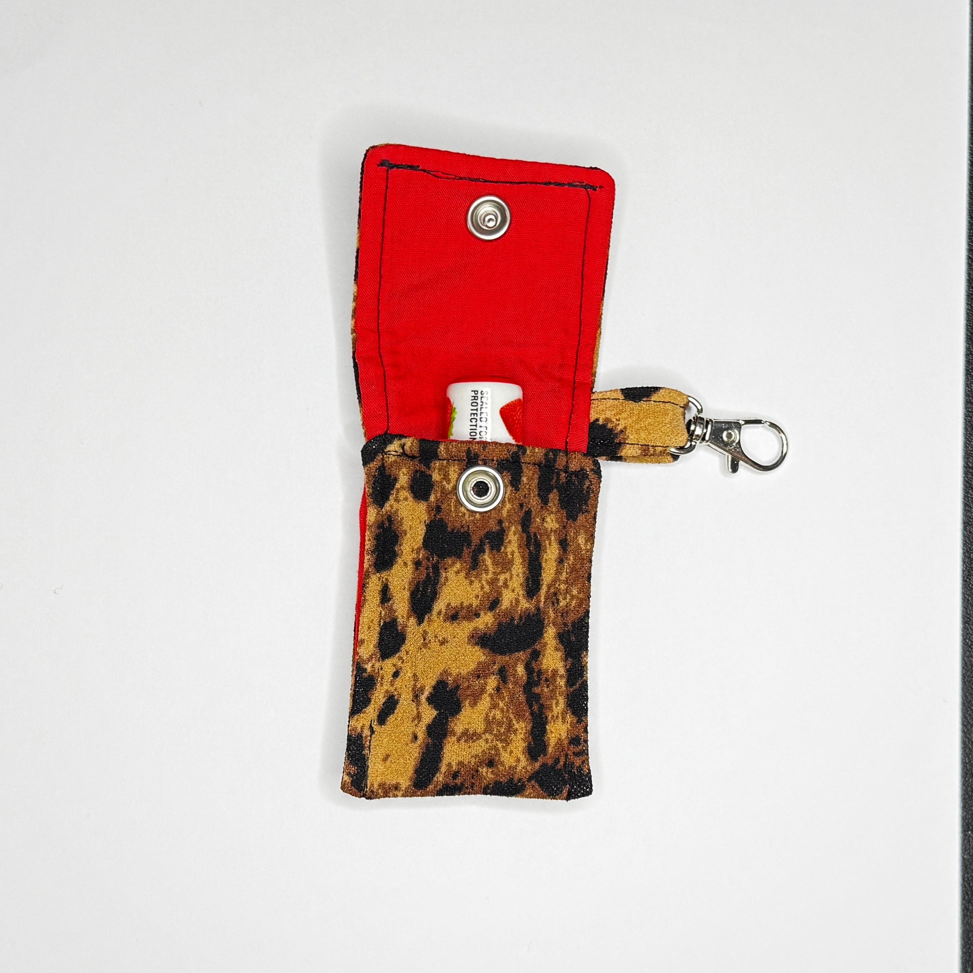Keep your favorite lip color or balm secure and stylishly close at hand with this handmade fabric keychain pouch. Perfectly capturing a timeless rockabilly aesthetic and retro pin-up glamour, this compact accessory ensures you never lose your essentials at the bottom of your bag again.