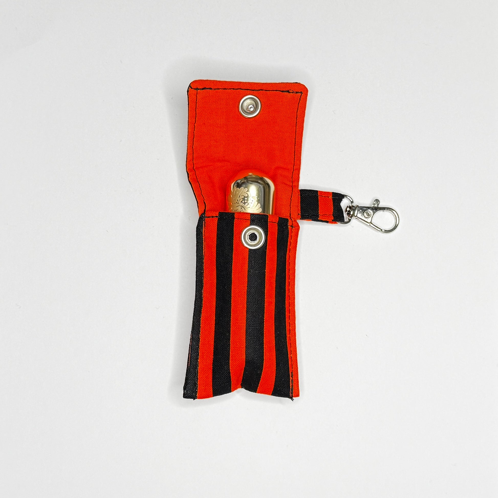 Keep your favorite lip color or balm secure and stylishly close at hand with this handmade fabric keychain pouch. Perfectly capturing a timeless rockabilly aesthetic, punk rock edge, and classic goth glamour, this compact accessory ensures you never lose your essentials at the bottom of your bag again.

This tailored fabric holder features a classic vertical stripe design in a high-contrast palette of vibrant orange and deep midnight black. Designed for ultimate everyday convenience, it includes a secure me