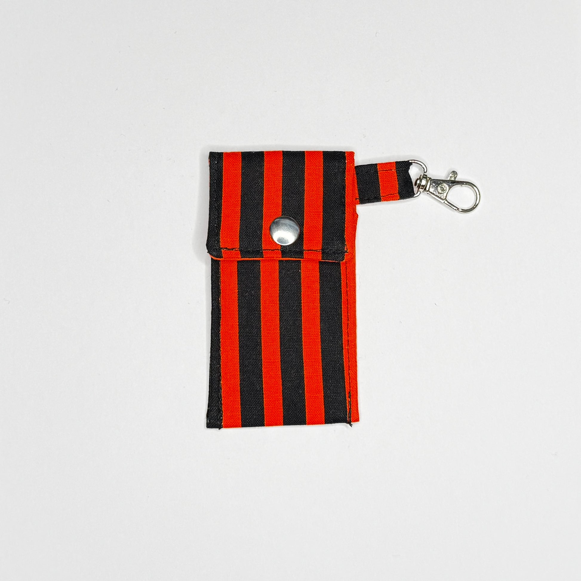 Keep your favorite lip color or balm secure and stylishly close at hand with this handmade fabric keychain pouch. Perfectly capturing a timeless rockabilly aesthetic, punk rock edge, and classic goth glamour, this compact accessory ensures you never lose your essentials at the bottom of your bag again.

This tailored fabric holder features a classic vertical stripe design in a high-contrast palette of vibrant orange and deep midnight black. Designed for ultimate everyday convenience, it includes a secure me
