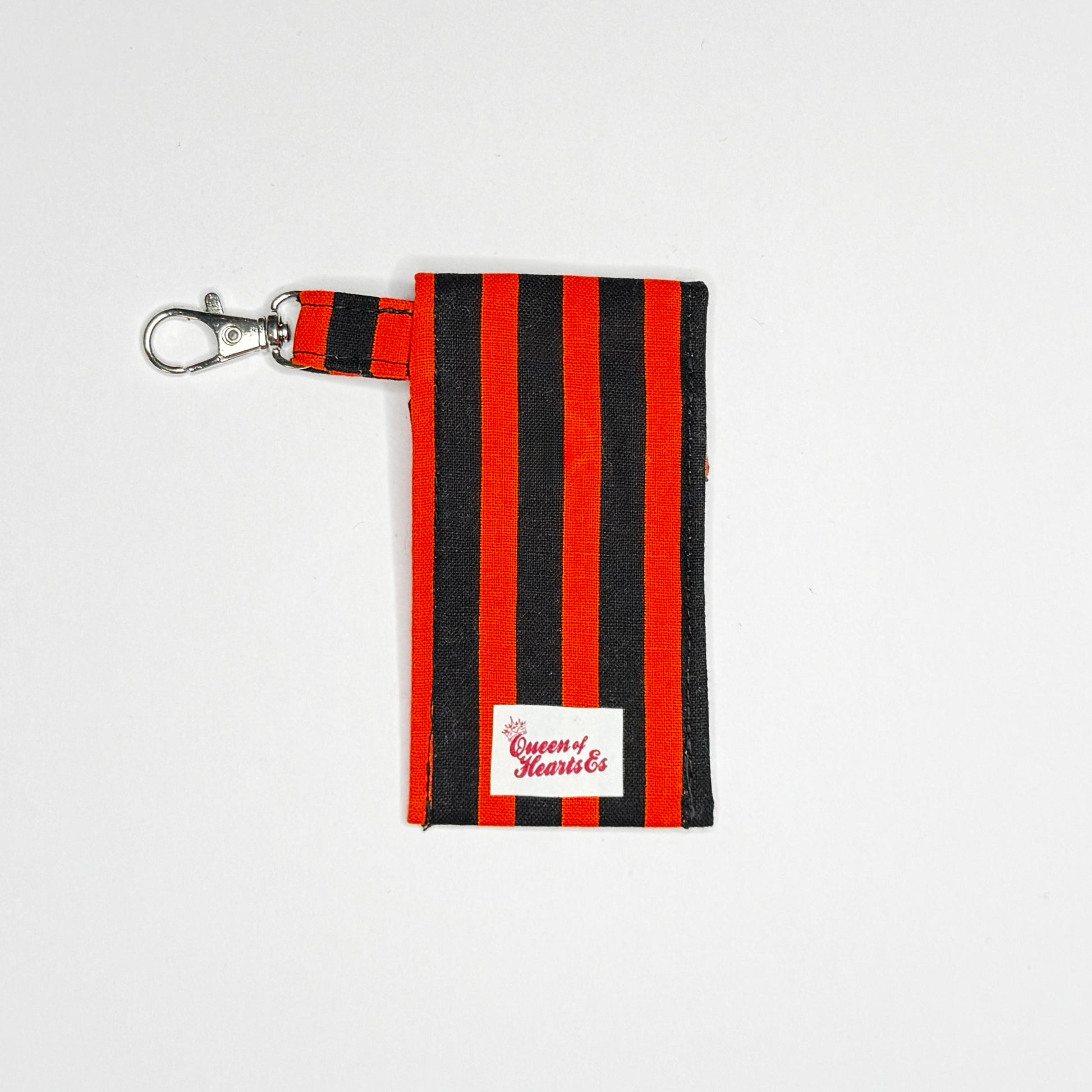 Keep your favorite lip color or balm secure and stylishly close at hand with this handmade fabric keychain pouch. Perfectly capturing a timeless rockabilly aesthetic, punk rock edge, and classic goth glamour, this compact accessory ensures you never lose your essentials at the bottom of your bag again.

This tailored fabric holder features a classic vertical stripe design in a high-contrast palette of vibrant orange and deep midnight black. Designed for ultimate everyday convenience, it includes a secure me