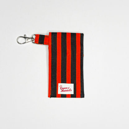 Keep your favorite lip color or balm secure and stylishly close at hand with this handmade fabric keychain pouch. Perfectly capturing a timeless rockabilly aesthetic, punk rock edge, and classic goth glamour, this compact accessory ensures you never lose your essentials at the bottom of your bag again.

This tailored fabric holder features a classic vertical stripe design in a high-contrast palette of vibrant orange and deep midnight black. Designed for ultimate everyday convenience, it includes a secure me