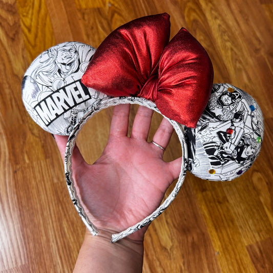Assemble your ultimate park outfit! Show off your love for Marvel with this awesome comic-book-inspired Minnie Mouse ears headband!

Featuring classic black-and-white comic panel graphics starring Avengers heroes (Thor, Captain America, Iron Man, Wolverine) paired with a bold, shimmering metallic red bow.