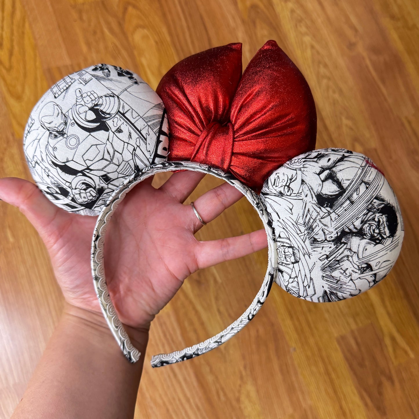 Assemble your ultimate park outfit! Show off your love for Marvel with this awesome comic-book-inspired Minnie Mouse ears headband!

Featuring classic black-and-white comic panel graphics starring Avengers heroes (Thor, Captain America, Iron Man, Wolverine) paired with a bold, shimmering metallic red bow.