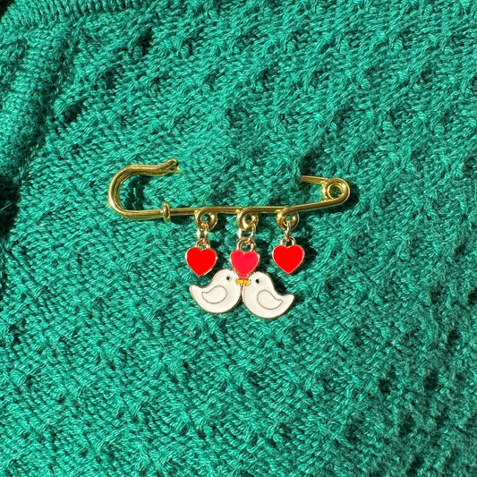 Elevate your Valentines Day or Galentines Day with this adorable gold iron pin brooch featuring love birds enamel charms. Perfect for adding a touch of love to any outfit.