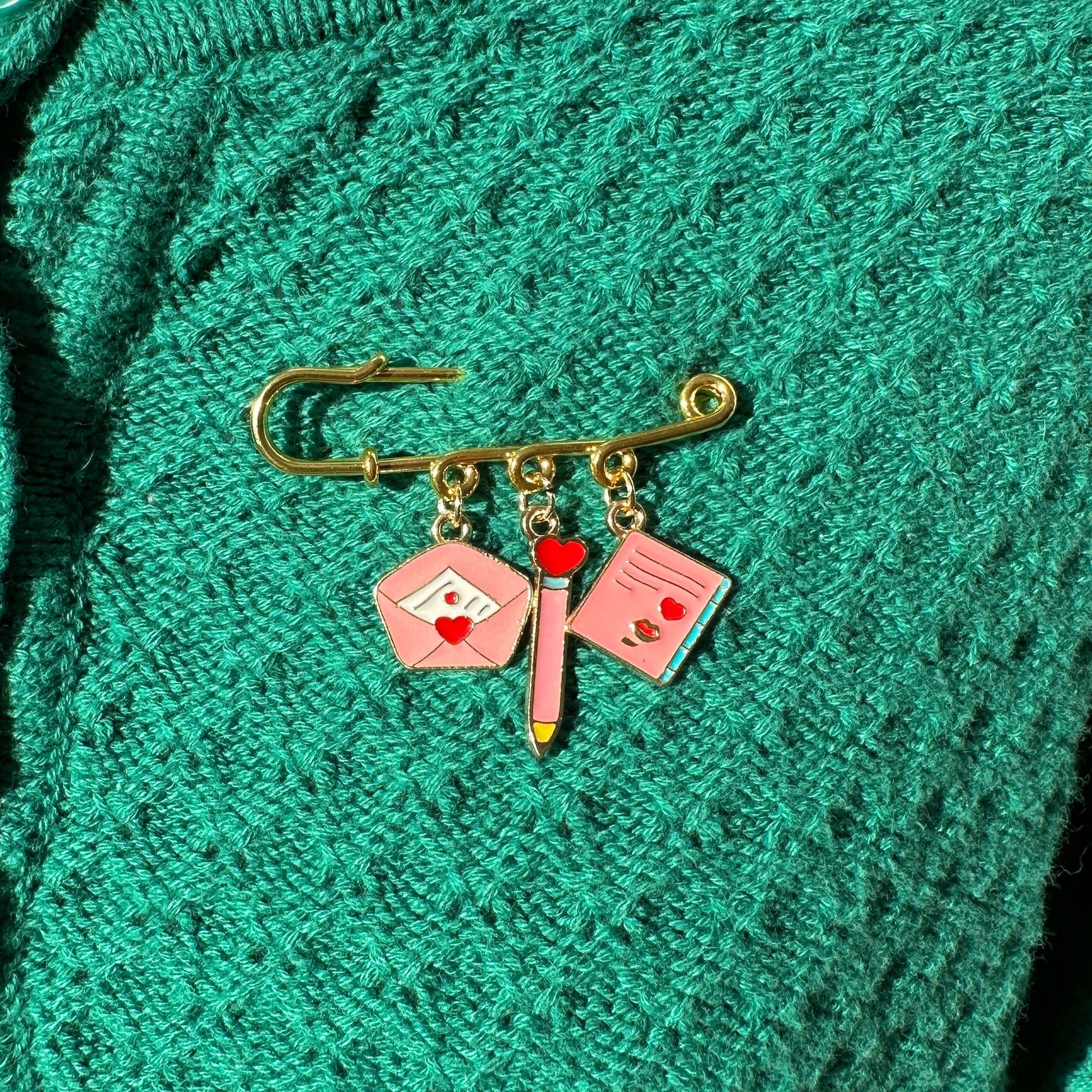 Elevate your Valentines Day or Galentines Day with this adorable gold iron pin brooch featuring love letter enamel charms. Perfect for adding a touch of love to any outfit.