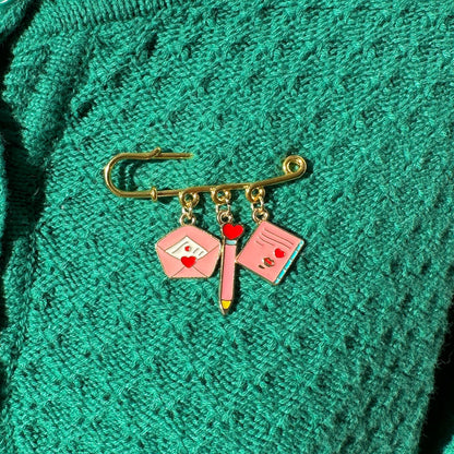 Elevate your Valentines Day or Galentines Day with this adorable gold iron pin brooch featuring love letter enamel charms. Perfect for adding a touch of love to any outfit.