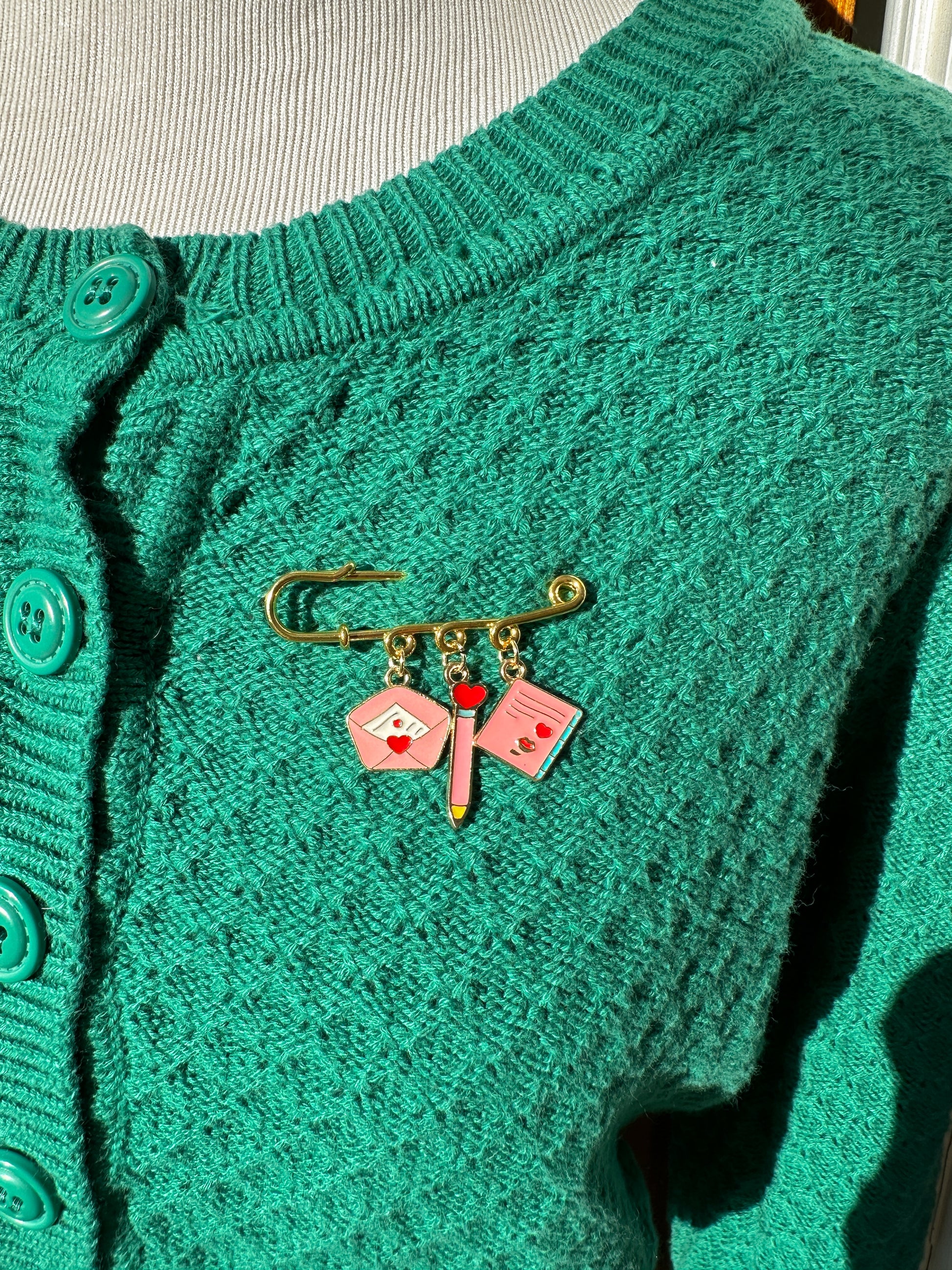 Elevate your Valentines Day or Galentines Day with this adorable gold iron pin brooch featuring love letter enamel charms. Perfect for adding a touch of love to any outfit.