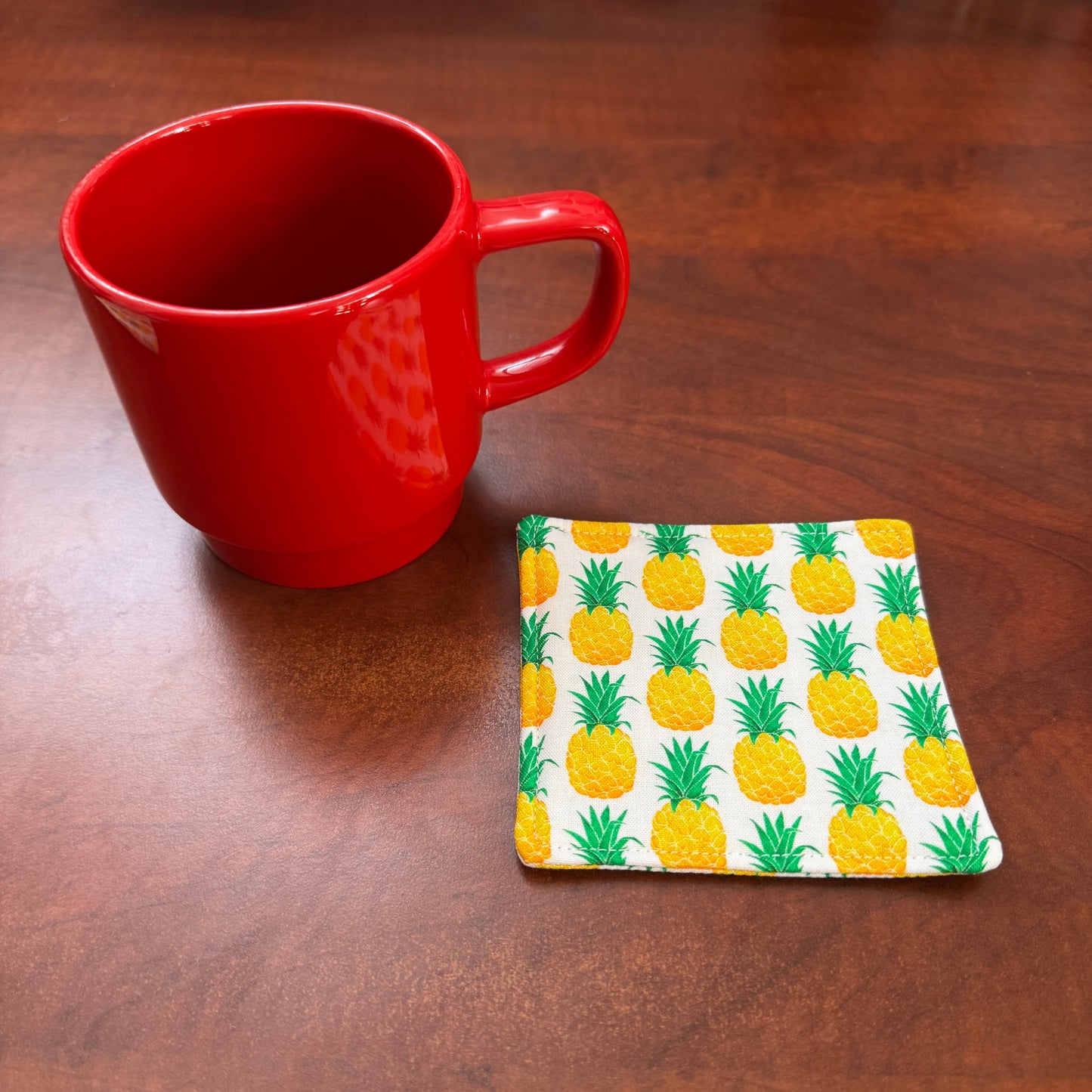 Keep your surfaces safe and stylish with our 100% cotton pineapple coaster. This charming coaster features a vibrant pineapple print that adds a touch of fresh, fruity fun to any room. Crafted with an absorbent cotton batting layer inside, it's designed to soak up condensation and protect your furniture from unsightly water rings and spills. Perfect for coffee mugs, glasses, or teacups, this durable and machine-washable coaster is a delightful addition to your kitchen or living room. Elevate your home decor
