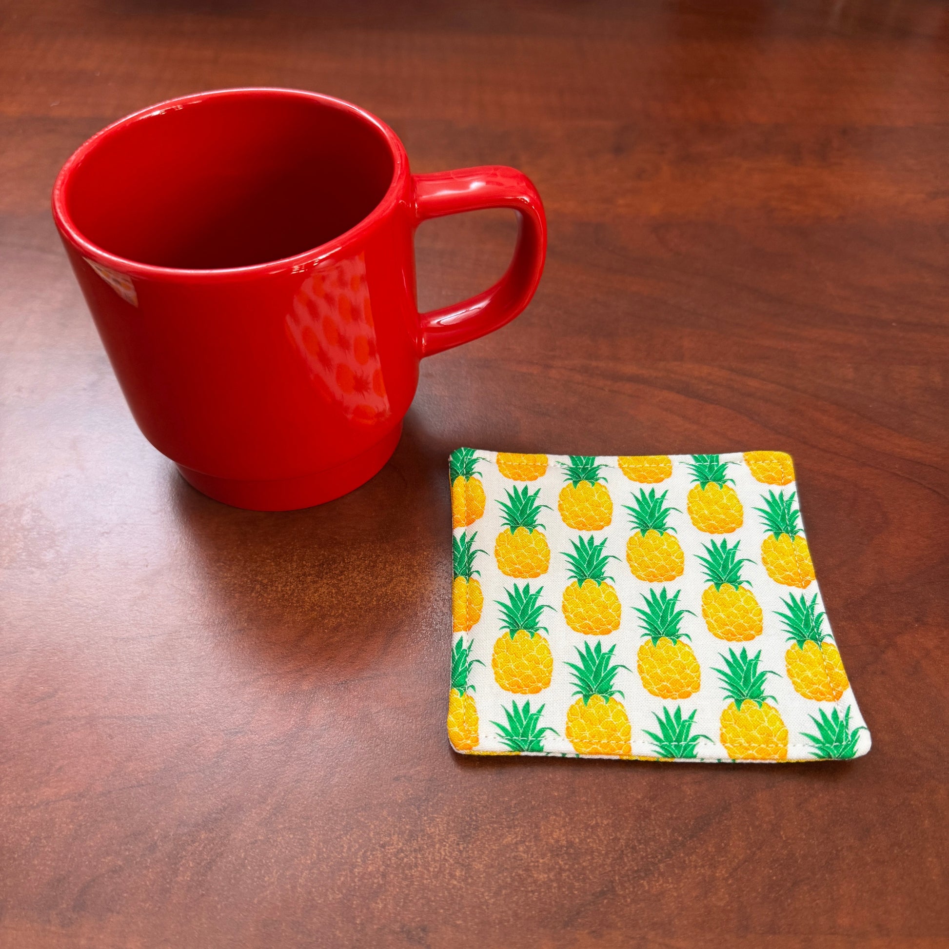 Keep your surfaces safe and stylish with our 100% cotton pineapple coaster. This charming coaster features a vibrant pineapple print that adds a touch of fresh, fruity fun to any room. Crafted with an absorbent cotton batting layer inside, it's designed to soak up condensation and protect your furniture from unsightly water rings and spills. Perfect for coffee mugs, glasses, or teacups, this durable and machine-washable coaster is a delightful addition to your kitchen or living room. Elevate your home decor