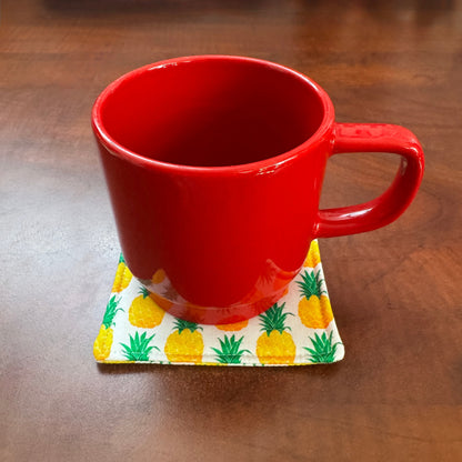 Keep your surfaces safe and stylish with our 100% cotton pineapple coaster. This charming coaster features a vibrant pineapple print that adds a touch of fresh, fruity fun to any room. Crafted with an absorbent cotton batting layer inside, it's designed to soak up condensation and protect your furniture from unsightly water rings and spills. Perfect for coffee mugs, glasses, or teacups, this durable and machine-washable coaster is a delightful addition to your kitchen or living room. Elevate your home decor