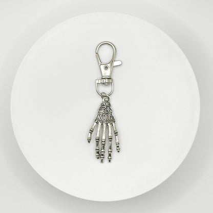 Grasp your style with our spooky skeleton hand charm! This unique, durable, and versatile accessory is perfect for horror fans and dark style lovers. Attach it to your bag, purse, or backpack for a touch of the macabre.