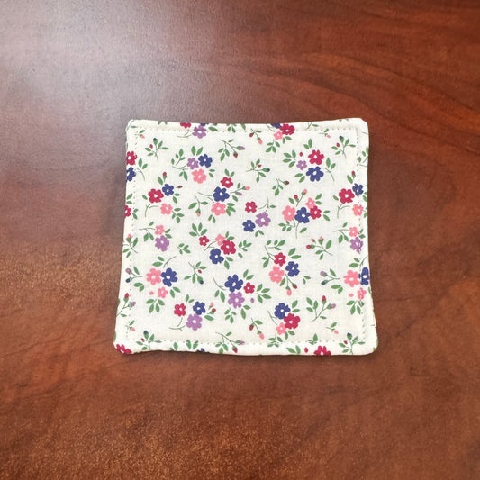 Elevate your space with this playful 100% cotton white floral coaster. Featuring a vibrant and stylish floral print, this coaster brings a touch of floral and fun to your home. Crafted with an absorbent cotton batting layer inside, it's designed to soak up condensation and protect your furniture from unsightly water rings and spills. Perfect for coffee mugs, glasses, or teacups, this durable and machine-washable coaster is a delightful addition to your kitchen or living room. Elevate your home decor with th