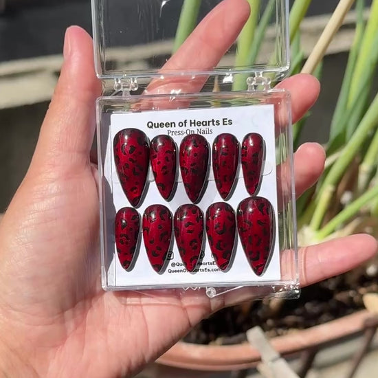Get ready for "The Fierce Feline" and embrace dark glamour with these stunning handmade press-on nails, featuring a red cat eye base and delicate, black leopard design.&nbsp;