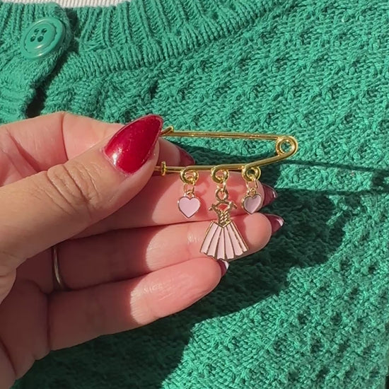 Elevate your Valentines Day or Galentines Day with this adorable gold iron pin brooch featuring pink dress enamel charms. Perfect for adding a touch of love to any outfit.