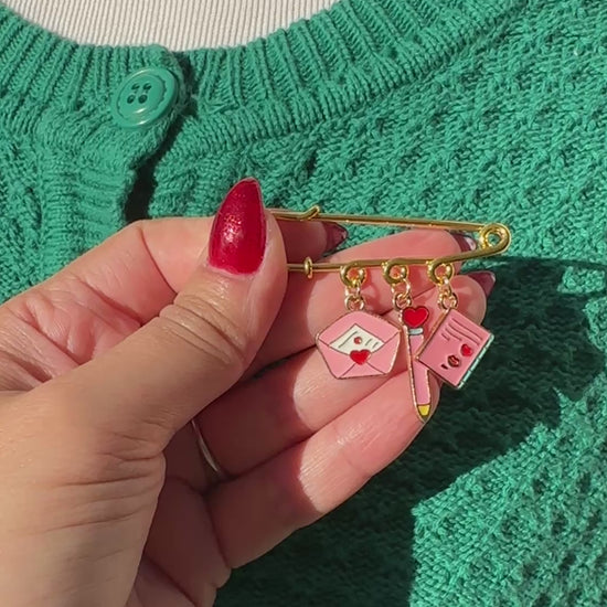 Elevate your Valentines Day or Galentines Day with this adorable gold iron pin brooch featuring love letter enamel charms. Perfect for adding a touch of love to any outfit.