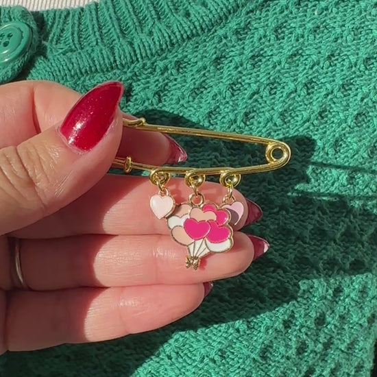 Elevate your Valentines Day or Galentines Day with this adorable gold iron pin brooch featuring heart balloons enamel charms. Perfect for adding a touch of love to any outfit.