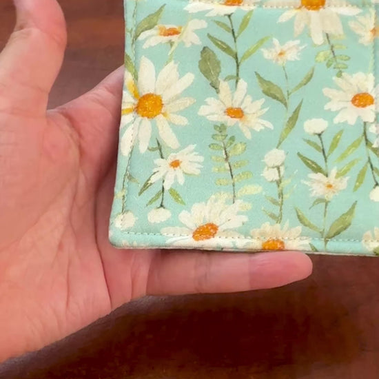 Elevate your space with this playful 100% cotton daisy coaster. Featuring a vibrant and stylish daisy print, this coaster brings a touch of tropical flair and fun to your home. Crafted with an absorbent cotton batting layer inside, it's designed to soak up condensation and protect your furniture from unsightly water rings and spills. Perfect for coffee mugs, glasses, or teacups, this durable and machine-washable coaster is a delightful addition to your kitchen or living room. Elevate your home decor with th