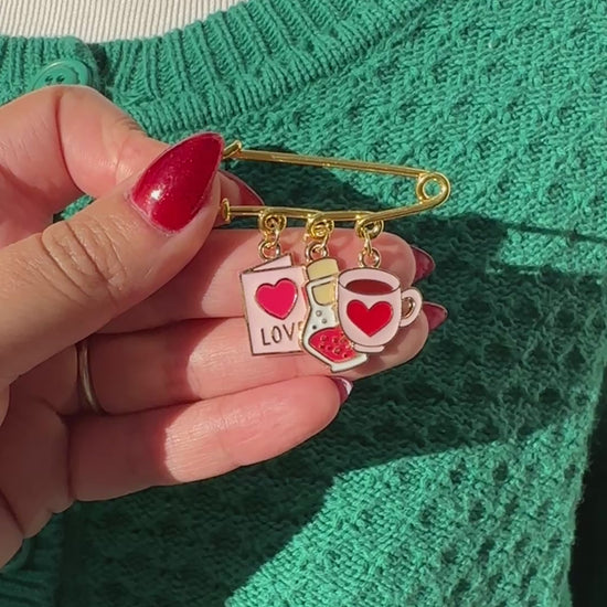 Elevate your Valentines Day or Galentines Day with this adorable gold iron pin brooch featuring love potion enamel charms. Perfect for adding a touch of love to any outfit.